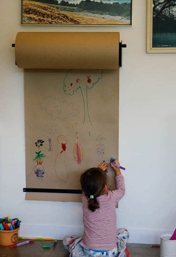 Ein
          Kind malt an einer Wand auf Packpapier