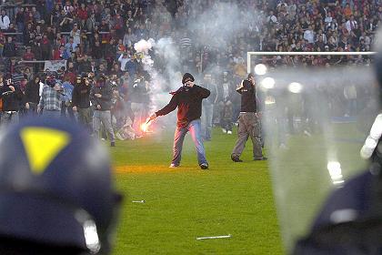 FCB-Krawalle
              vom 13.5.2006: Basler Schlgertyp auf dem Spielfeld beim
              Wurf mit einer brennenden Petarde, bei vollstem Risiko der
              schwersten Krperverletzung.