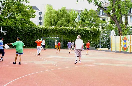 Combi playground in
                              red at the school of Schanzengraben in
                              Zurich, soccer and handball lengthwise,
                              basketball crossways