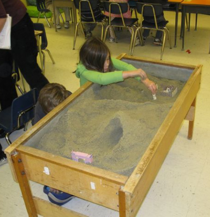 Sandkiste mit Sand,
                            Autos, Tunnel und Haus, Grundschule Gibson,
                            "USA"